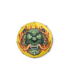 A vibrant green tiger with a mouth full of orange flames in front of a yellow background. Real barbed wire wraps around the circular wood panel.