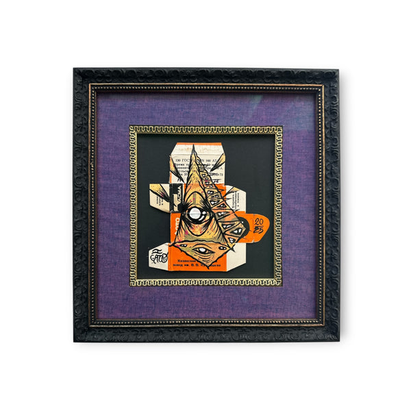 Custom black frame mixed media Eye Gato artwork painted on vintage 35mm film packaging, featuring the pyramid eye character in orange, black, and peach tones within a purple mat board and gold trim.
