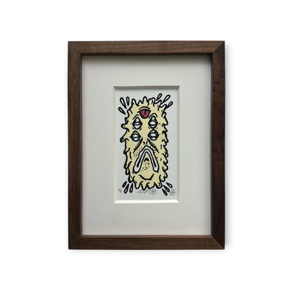 Cream colored Eye Gato Abductor character with black outline and red tongue on top. Mounted on white boards with a custom brown wood frame.