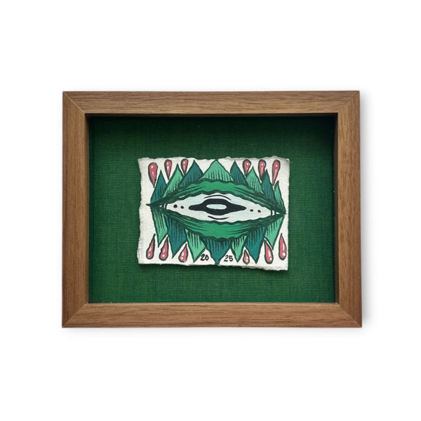 Brown walnut custom frame with green eye and red water drops on white rives paper while mounted on a textured green board.