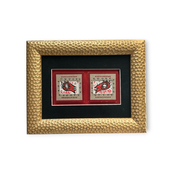 Two red and black hand-drawn eyes on vintage Kodachrome packaging, mounted on red and black boards. Custom framed in a hammered gold textured wood frame by Eye Gato.