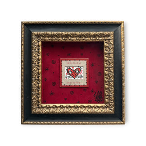 Red heart with eyes art on a piece of vintage Kodachrome film packaging. Mounted on red felt and set in a black and gold baroque-style textured wood frame.