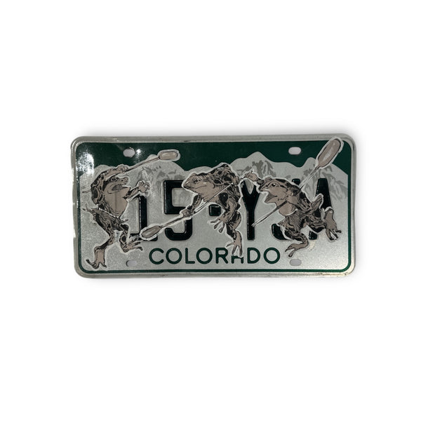 Black and white frog trio wheat pasted onto a green and silver Colorado license plate.