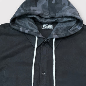 Close-up of black and dark gray camo pattern on custom-stitched hood, around the collar of the black colored painters cotton jacket.