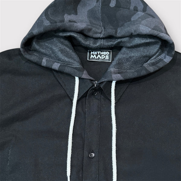 Close-up of black and dark gray camo pattern on custom-stitched hood, around the collar of the black colored painters cotton jacket.